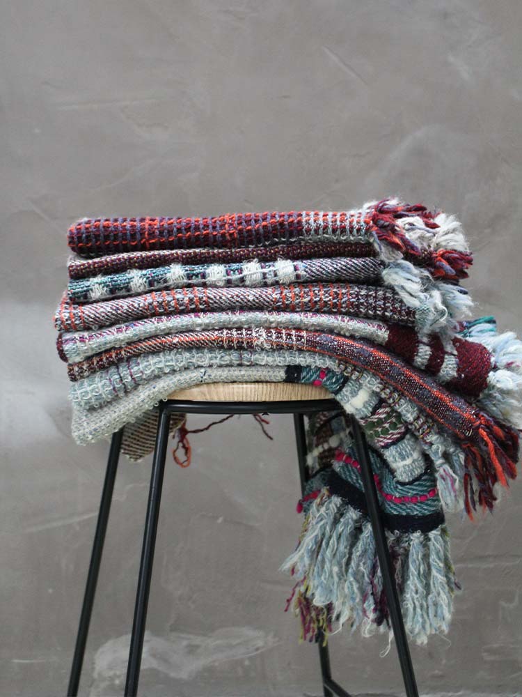 A stack of blankets neatly arranged on a stool, providing warmth and comfort.