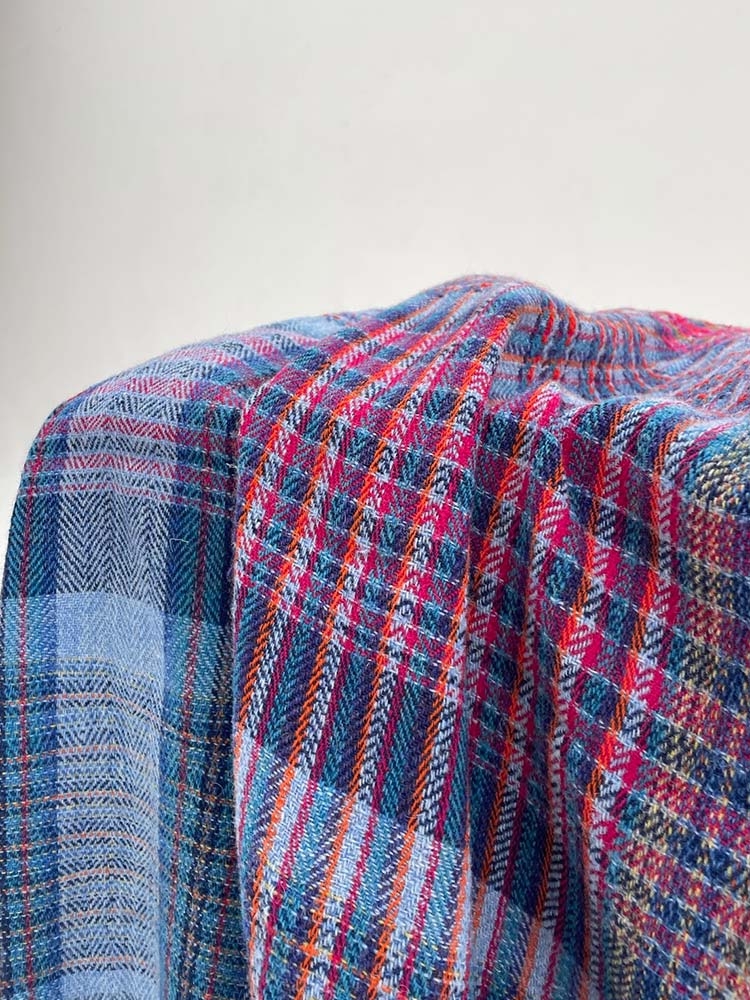 A blue and red plaid blanket neatly laid on a white surface, creating a cozy and stylish contrast.