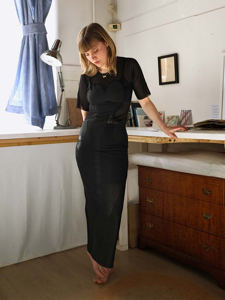 Elegant woman in black dress standing indoors.