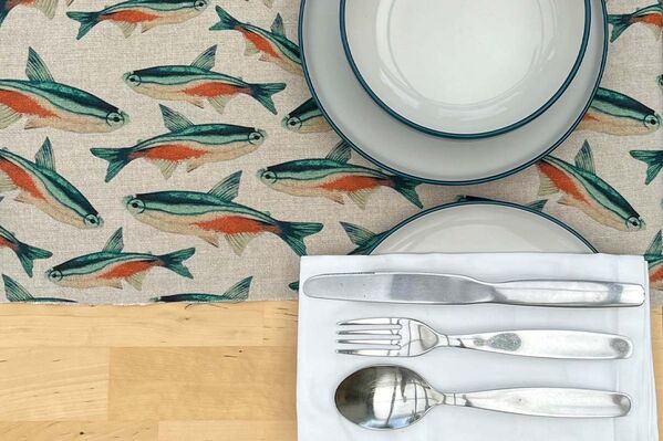 A table with a fish-patterned tablecloth and silverware, creating an elegant and aquatic ambiance.