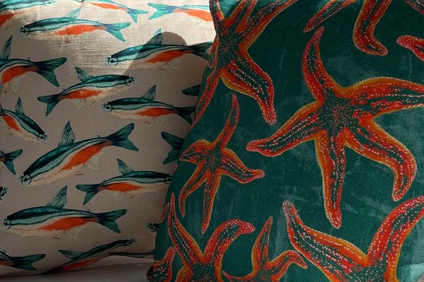 Two decorative pillows featuring fish and starfish designs.