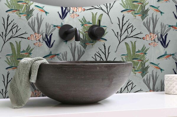 Fish-themed wallpaper in bathroom with sink.