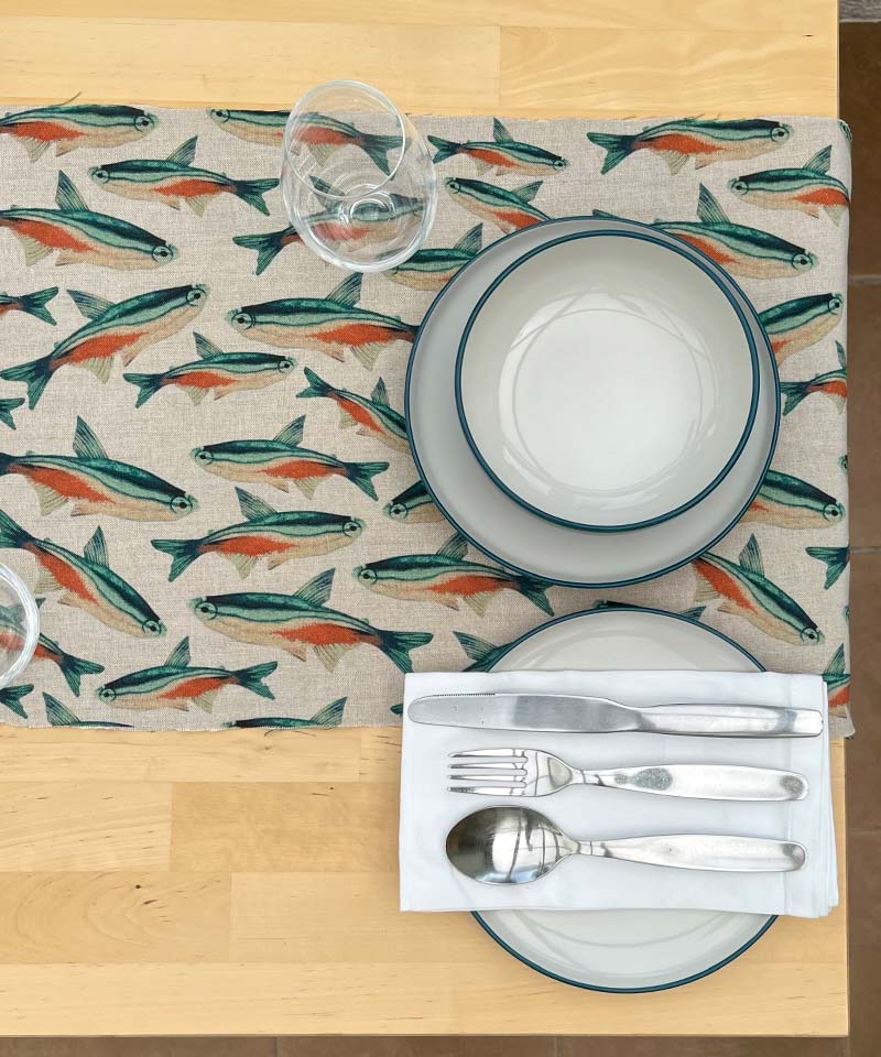 A table with a place mat featuring fish designs.