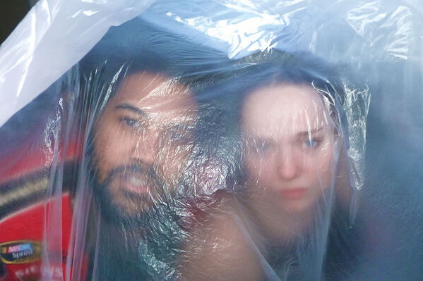 A man and woman peer out through a sheet of semi-opaque plastic