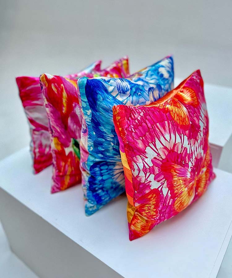 Four vibrant tie-dye pillows showcasing colorful designs.