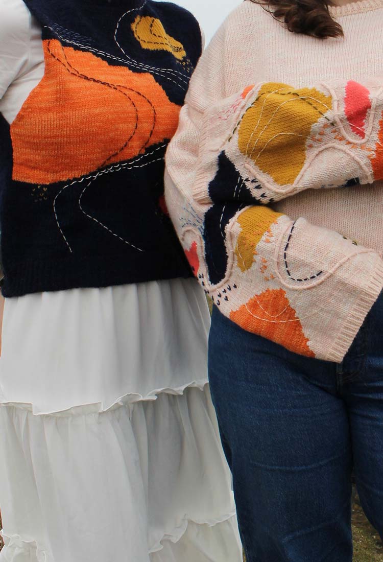 Two women in vibrant sweaters and jeans.