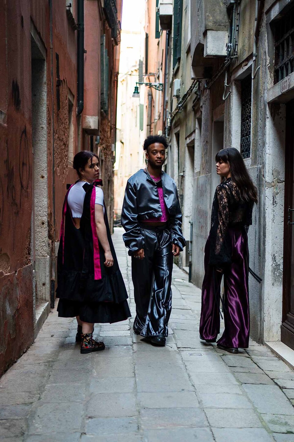 A man and two women modelling Flamenco inspired streetwear from a collection by Paula Pacheco ina narrow street in Seville