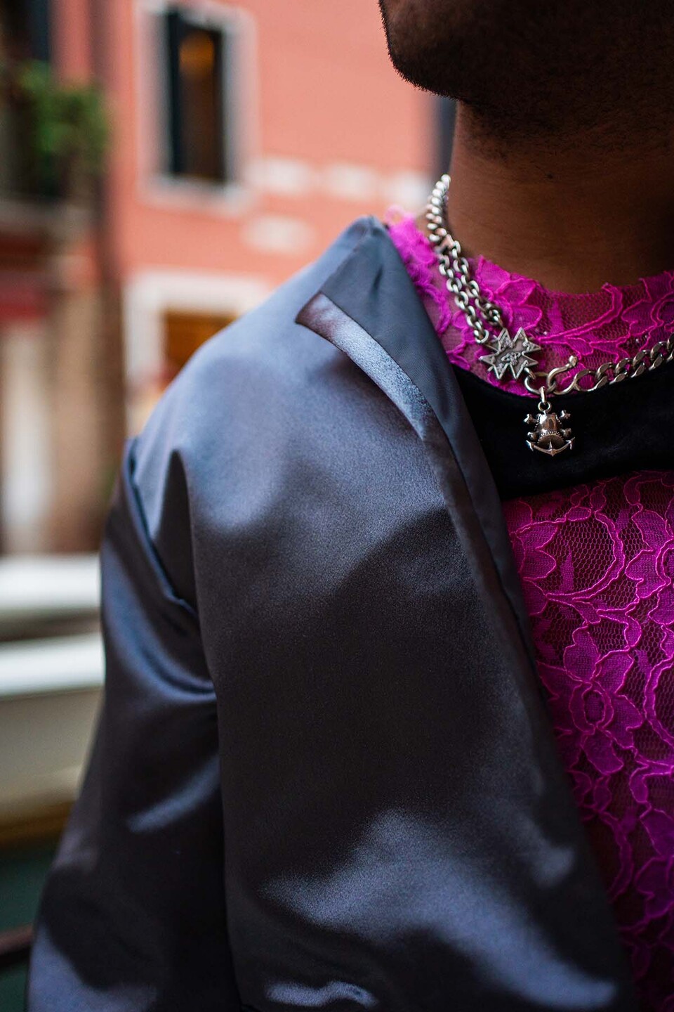 Close up of a top, jacket and neck chain worn by a man modelling Flamenco inspired streetwear from a collection by Paula Pacheco in a street in Seville