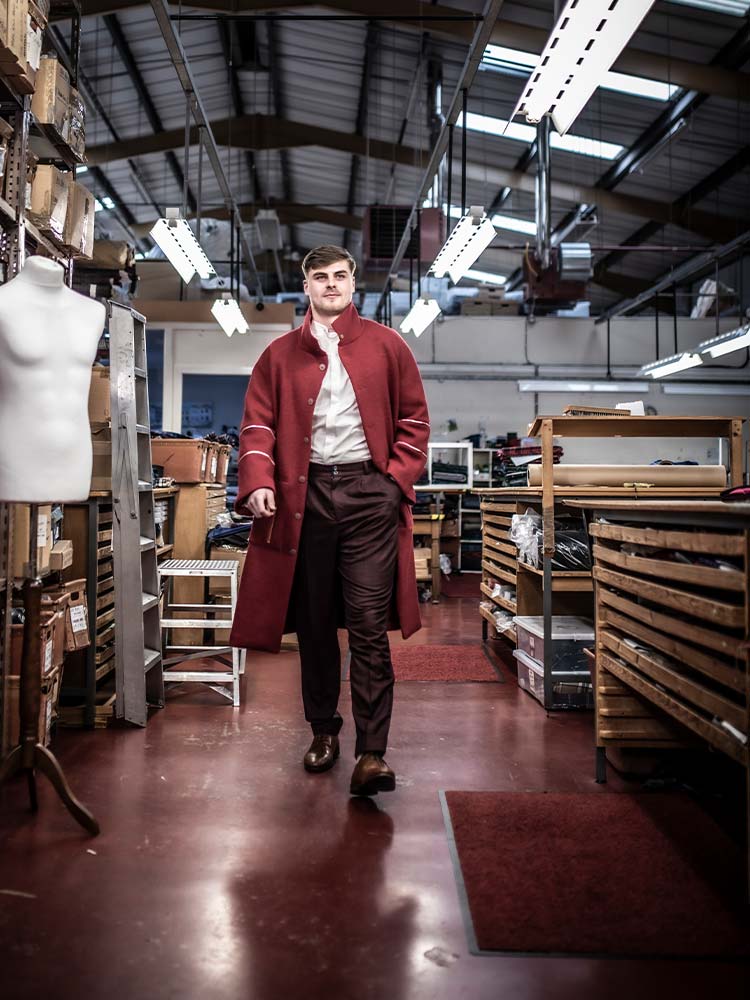 A man in a red coat walking through a factory, inspecting machinery and equipment.