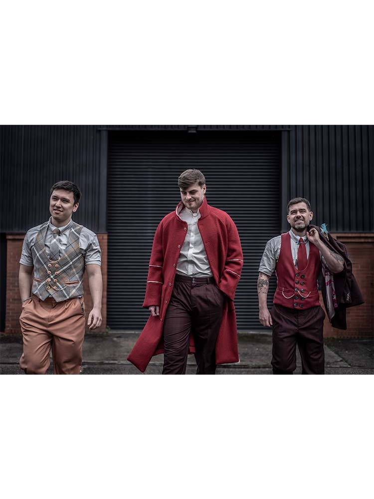 Three men in red coats and ties walking down the street in a formal and stylish manner.
