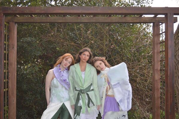 Three women model bridal wear made from hand dyed, second hand wedding dresses and silk fabrics unde a pergola.