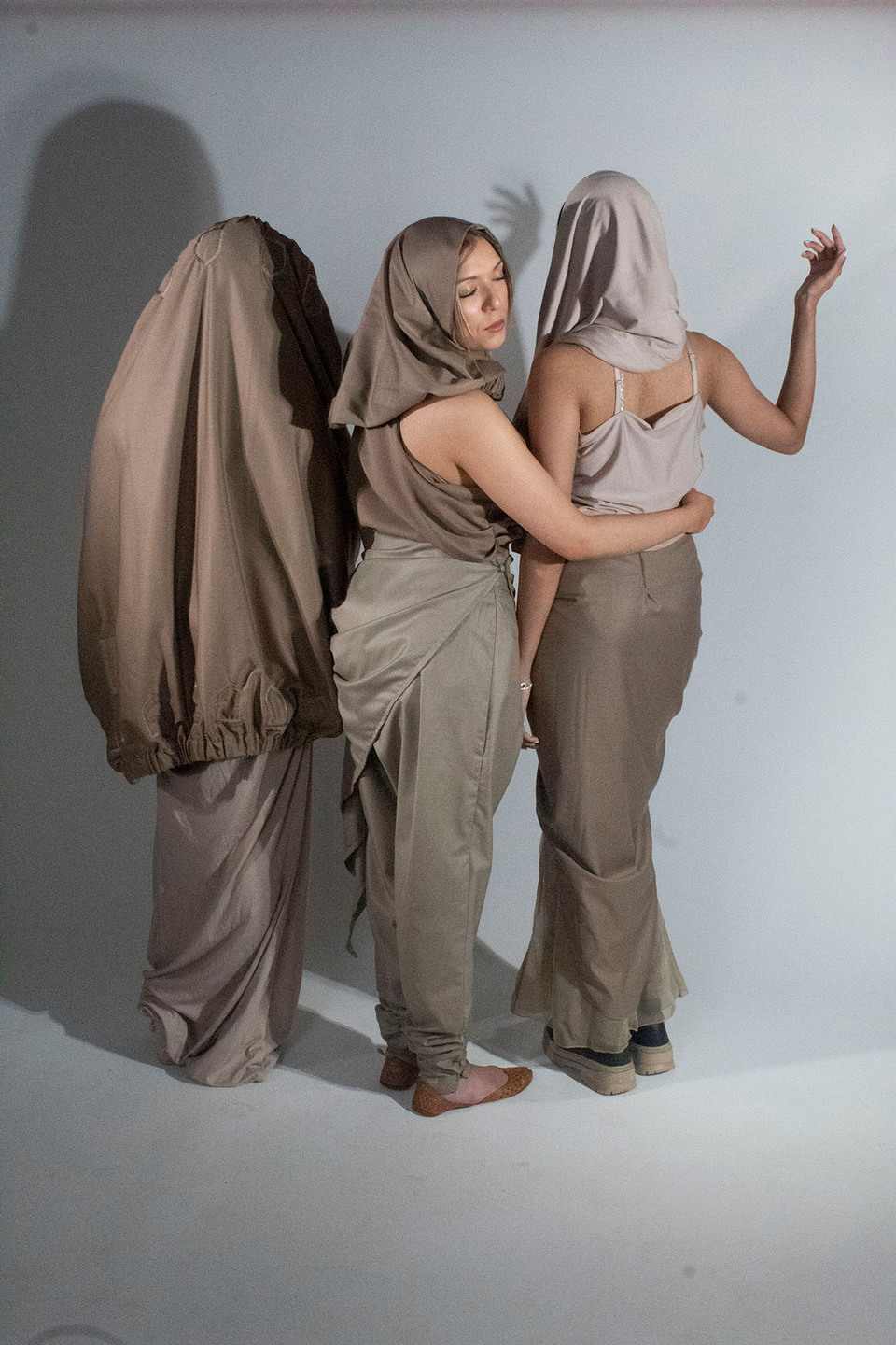 Rear view of three women modelling dresses, trousers and headscarves inspired by traditional Yemeni clothing with a futurist twist