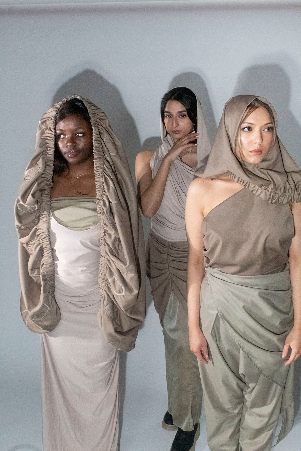 Three women model dresses, trousers and headscarves inspired by traditional Yemeni clothing with a futurist twist