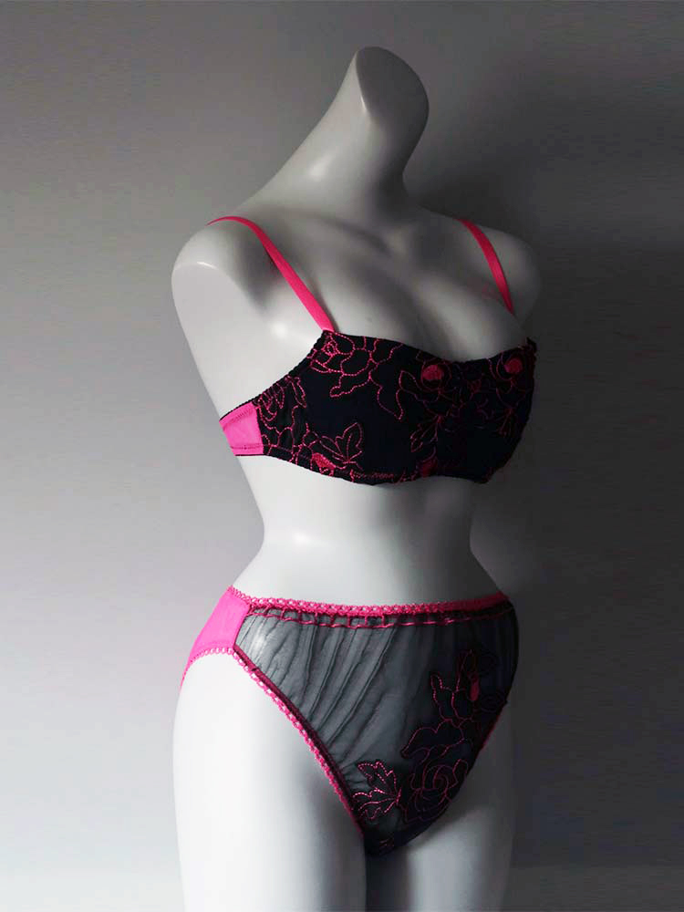A mannequin wearing a pink bra and black underwear, showcasing a stylish and alluring lingerie set.