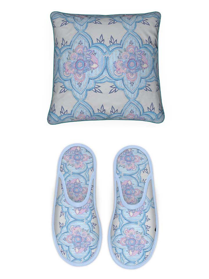 A blue and white pillow and slippers with a blue floral pattern.
