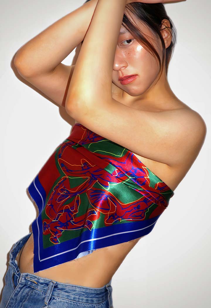 Portrait of woman in red, green and blue silk scarf posing for camera.