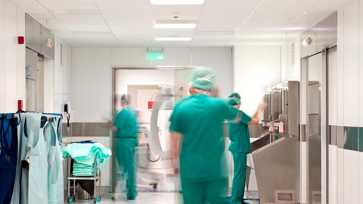 Hospital doctors wearing green protective clothing, hair coverings and face masks.